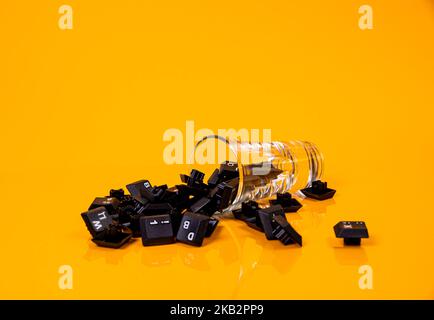 Tastatur-Taste in Glas in Eimer auf orangefarbenem Hintergrund isoliert Hacker Stockfoto