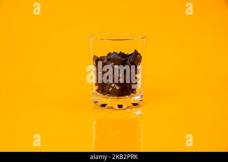 Tastatur-Taste in Glas in Eimer auf orangefarbenem Hintergrund isoliert Hacker Stockfoto