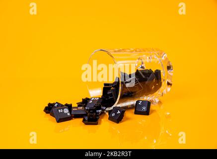 Tastatur-Taste in Glas in Eimer auf orangefarbenem Hintergrund isoliert Hacker Stockfoto