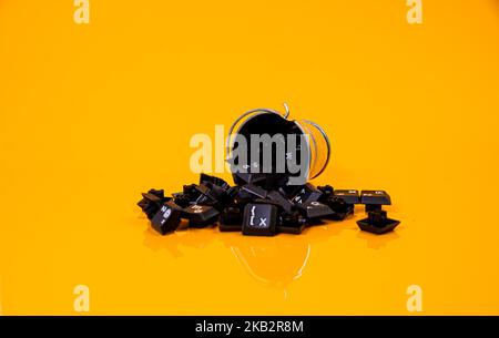 Tastatur-Taste in Glas in Eimer auf orangefarbenem Hintergrund isoliert Hacker Stockfoto
