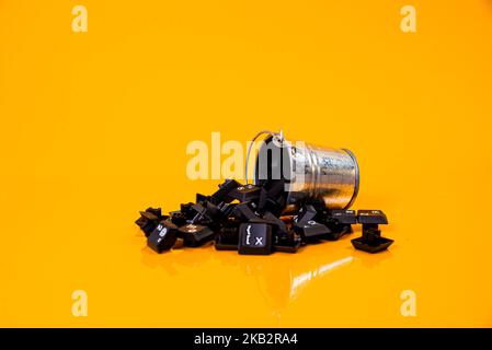 Tastatur-Taste in Glas in Eimer auf orangefarbenem Hintergrund isoliert Hacker Stockfoto