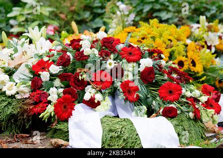 rosen, Gerbera, Lilien und Sonnenblumen auf einem Grab nach einer Beerdigung Stockfoto