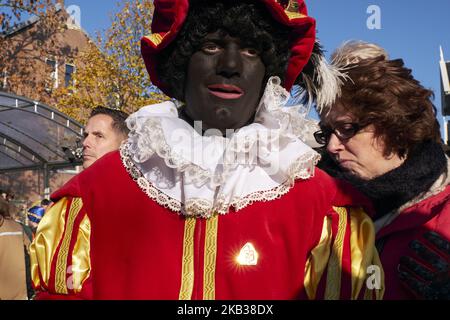 Am 17. November 2018 nahmen mehrere Personen an der Veranstaltung Teil, die als Zwarte Piet. In Zaandam, Niederlande, getarnt waren. Der heilige Nikolaus kommt noch ein Jahr von Spanien nach Holland. Dieses Jahr wurde dieses Fest in der Stadt Zaandam, die für ihre malerischen Windmühlen berühmt ist, landesweit gefeiert. Von dort aus wird der Nikolaus in die übrigen niederländischen Städte fahren. Wieder einmal wurde die Feier von der Kontroverse beeinflusst, die von antirassistischen Gruppen geschaffen wurde, die diese Tradition des Habens rassistischer Komponenten beschuldigen. Insbesondere in der Figur von Zwarte Piet, einer Figur, die als schwarzes M erscheint Stockfoto