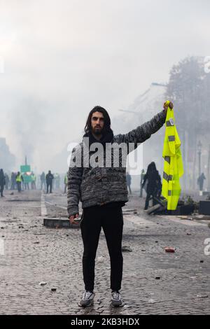 Paris, Frankreich, 24. November 2018. Ein Protestant mit einer gelben Weste in der Handfahne steht vor der Polizei während eines Protests von Gelbwesten (Gilets Jaunes) gegen steigende Ölpreise und Lebenshaltungskosten in der Nähe des Triumphbogens auf den Champs Elysees. Sicherheitskräfte in Paris feuerten Tränengas und Wasserwerfer ab, um Demonstranten zu zerstreuen. (Foto von Emeric Fohlen/NurPhoto) Stockfoto