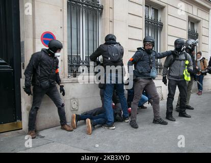 Die Polizei verhaftete während der Demonstration gegen die Steuererhöhungen in der Avenue des Champs-Élysées in Paris einen Demonstranten mit französischer Flagge. Am 8. Dezember 2018 in Paris, Frankreich. In der vierten Woche in Folge versammelten sich am 8. Dezember 2018 Tausende von Menschen mit gelben Westen auf den Champs-Elysées in Paris, um gegen die französische Regierung zu protestieren Stockfoto