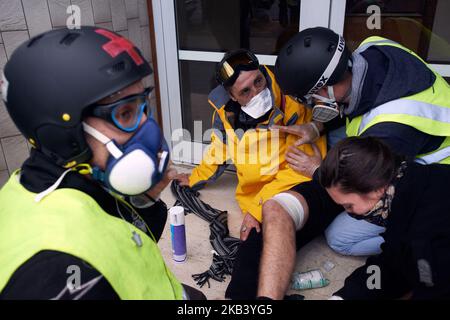 Sanitäter der gelben Westen helfen einem verletzten Mann mit einem Flashball im Bein und beruhigen ihn. Die Gelbwesten demonstrierten zum 4.-mal wieder. Freiwillige Sanitäter kamen, um Verletzten erste Hilfe zu leisten und waren irritiert über Tränengas, das die Bereitschaftspolizei während des Protestes und während des Aufruhrs ausgab. Die Proteste der Gelbwesten begannen als Protest gegen die steigenden Kraftstoffsteuern, und jetzt lehnen sie Macrons Politik ab und forderten seinen Rücktritt. Mehr als 10 000 Menschen gingen auf die Straße. Am 8. Dezember 2018 in Toulouse, Frankreich. (Foto von Alain Pitton/NurPhoto) Stockfoto