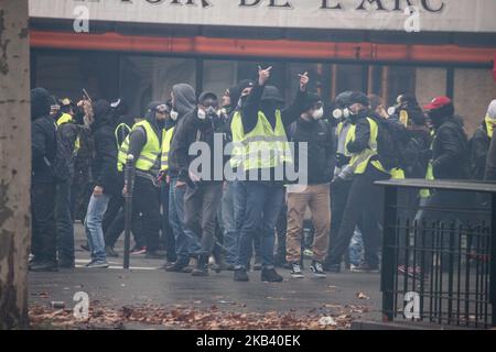 Demonstranten zeigen den Mittelfinger, der während der Gelbwesten-Demonstration in der Nähe des Arc de Triomphe in Tränengasrauch gesehen wird. Zusammenstöße und Vandalismus, die zu Tausenden von Verhaftungen geführt haben, darunter mehr als 1.700 am Samstag, den 8. Dezember 2018, als Folge der Proteste der ‘Gelbwesten’, einer Anti-Regierungsbewegung. Straßensperren und viele Aktionen unter den Demonstranten und der Polizei ereigneten sich um den Arc de Triomphe und die Champs Elysees mit kaputten Geschäften, verbrannten oder beschädigten Autos, Straßensperren mit Feuer, Gewalt und viel Tränengasrauch von der Polizei. (Foto von Nicolas Economou/NurPhoto) Stockfoto