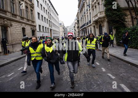 Die Demonstranten von Gilets Jaunes („Gelbe Weste“) laufen am 15. Dezember 2018 bei einer Demonstration auf der Champs Elysees Avenue in Paris, Frankreich, vor der französischen Bereitschaftspolizei. Obwohl die französischen Minister an die landesweiten Proteste der „Gilets Jaunes“ („Gelbe Weste“) appellieren, nach dem Anschlag in Straßburg, bei dem am 11. Dezember drei Menschen getötet wurden, aufzuhören, gingen die Demonstranten am fünften Samstag in Folge auf die Straßen Frankreichs. Die Bewegung „Gilets Jaunes“ („Gelbe Weste“), die am 17. November 2018 begann und von der Opposition gegen eine neue Kraftstoffsteuer inspiriert wurde, hat eine breite Palette regierungsfeindlicher Senzeit aufgenommen Stockfoto