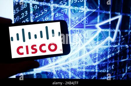 Das Logo von Cisco Systems ist auf einem Bildschirm eines Smartphones neben einem Bildschirm mit einer Abbildung der Börse zu sehen. Cisco ist an der Nasdaq notiert. Die Nasdaq ist nach der New Yorker Börse die zweitgrößte Börse der Welt. (Foto von Alexander Pohl/NurPhoto) Stockfoto