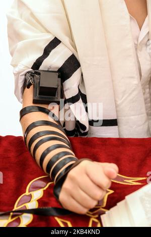 Ein junger Mann mit jüdischen Tefillin auf seine Hand und tragen Gebetsschal für das Gebet Stockfoto