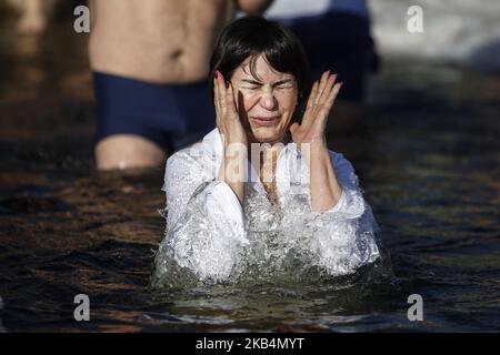 Eine Frau reagiert beim Tauchen in eisigen Gewässern, um die orthodoxe Epiphanie in Kiew, Ukraine, am 19. Januar 2019 zu feiern. Die orthodoxen Christen feiern die Epiphanie, indem sie sich auf dem Dnjepr-Fluss in Kiew in Gewässer mit Temperaturen unter Null Grad eintauchen. (Foto von Diego Herculano/NurPhoto) Stockfoto