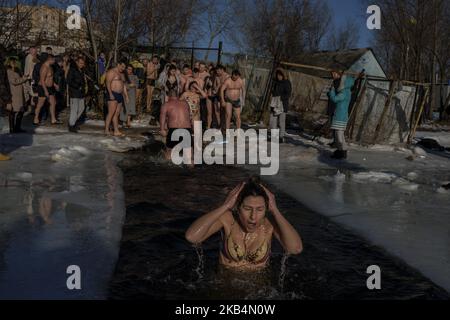 Eine Frau reagiert beim Tauchen in eisigen Gewässern, um die orthodoxe Epiphanie in Kiew, Ukraine, am 19. Januar 2019 zu feiern. Die orthodoxen Christen feiern die Epiphanie, indem sie sich auf dem Dnjepr-Fluss in Kiew in Gewässer mit Temperaturen unter Null Grad eintauchen. Die orthodoxen Christen feiern die Epiphanie, indem sie sich auf dem Dnjepr-Fluss in Kiew in Gewässer mit Temperaturen unter Null Grad eintauchen. (Foto von Diego Herculano/NurPhoto) Stockfoto