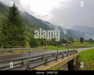 Straße, die durch eine Brücke in der Nähe eines kleinen Dorfes in Österreich führt Stockfoto