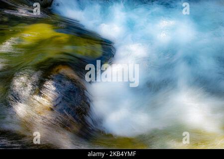 Langzeitbelichtung abstraktes Bild von wirbelndem Wasser in einem Bergfluss aus kristallklarem Wasser, grünen, blauen und weißen Tönen Stockfoto