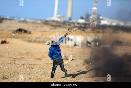 Ein palästinensischer Protestler schleudert am 29. Januar 2019 während der Zusammenstöße entlang der Grenze zum Gazastreifen einen Stein auf die israelischen Streitkräfte. - Die Palästinenser versammeln sich seit fast einem Jahr mindestens wöchentlich an verschiedenen Orten entlang der Grenze zu Gaza zu häufig gewalttätigen Protesten. Sie wollen in die Häuser zurückkehren können, vor denen ihre Familien im Krieg um die Gründung Israels im Jahr 1948 geflohen sind, sowie die Blockade des jüdischen Staates in Gaza beenden können. (Foto von Majdi Fathi/NurPhoto) Stockfoto