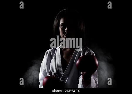 Schönes Mädchen Ausübung Karate Pose und Schreien vor Nebel Hintergrund Stockfoto