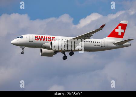 Swiss Airlines Bombardier BD-500 CSeries CS100 oder Airbus A220-100 wie bei der endgültigen Landung auf dem internationalen Flughafen London Heathrow LHR EGLL in England, Großbritannien, während eines bewölkten Sommertages gesehen. Das moderne Flugzeug hat die Zulassung HB-JBB, 2x Pratt & Whitney PW1524G Jet-Triebwerke und den Namen Canton de Genève. Swiss International Air Lines LX SWR ist die Schweizer Flaggengesellschaft, die sich im Besitz der Lufthansa Group befindet und Mitglied der Star Alliance Aviation Group ist. Die Fluggesellschaft war der weltweit einführende Kunde von Canadian Bombardier CS100/CS300, jetzt A220, die sowohl als regionale als auch als Mittelstreckenflüge durchgeführt wurden Stockfoto