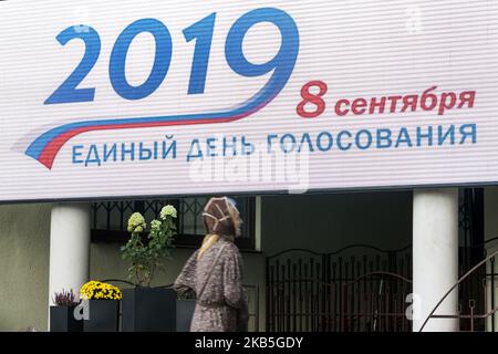 Frau unter einem riesigen Wahlbanner am Eingang eines Wahllokals während des Wahltages für die Moskauer Stadtratswahlen am 8.. September 2019 in Moskau, Russland. Die Wahlen sollen im System der ersten Wahl nach der Post stattfinden: 45 Abgeordnete sollen in 45 Wahlkreisen mit einem einzigen Mitglied gewählt werden. Die Laufzeit der neuen Duma wird fünf Jahre betragen. (Foto von Celestino Arce/NurPhoto) Stockfoto