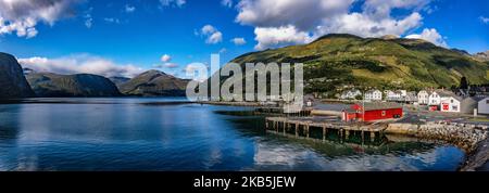 Panorama von Valldal oder Valldalen Angeln oder Sylte im Valldal Tal mit traditionellen Häusern, Kirche, Tankstelle, Tunnel, der Fjord umgeben von Bergen in Norddal Gemeinde in Møre Og Romsdal Kreis in Norwegen. Es gibt steile Hügel und alpine Berge mit Gletschern rund um, fließt der Valldola Fluss das fruchtbare Tal mit vielen Wasserfällen in den benachbarten Hügeln geschaffen. Das Dorf ist berühmt und beliebt bei Touristen und Besuchern, da es mit der Fähre zum Sognefjord und Geiranger Fjord und Trollstigen von der anderen Seite, Teil der norwegischen Nationalstraße 63, verbindet. (Foto von Nicolas Stockfoto