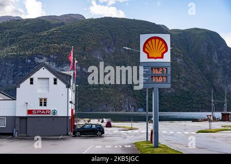 Shell-Tankstelle vor dem Fjord in Valldal oder Valldalen Angeln oder Sylte im Valldal Tal mit traditionellen Häusern, Kirche, Tankstelle, Tunnel, der Fjord umgeben von Bergen in Norddal Gemeinde in Møre Og Romsdal Kreis in Norwegen. Es gibt steile Hügel und alpine Berge mit Gletschern rund um, fließt der Valldola Fluss das fruchtbare Tal mit vielen Wasserfällen in den benachbarten Hügeln geschaffen. Das Dorf ist berühmt und beliebt bei Touristen und Besuchern, da es mit der Fähre zum Sognefjord mit dem Geiranger Fjord und Trollstigen von der anderen Seite, einem Teil der norwegischen Natio, verbindet Stockfoto