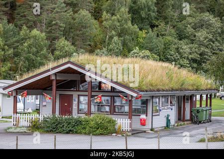 Bauen mit Pflanzen des Daches, eine umweltfreundliche Lösung für die Isolierung in Valldal oder Valldalen Angeln oder Sylte im Valldal Tal mit traditionellen Häusern, Kirche, Tankstelle, Tunnel, der Fjord umgeben von Bergen in Norddal Gemeinde in Møre Og Romsdal Kreis in Norwegen. Es gibt steile Hügel und alpine Berge mit Gletschern rund um, fließt der Valldola Fluss das fruchtbare Tal mit vielen Wasserfällen in den benachbarten Hügeln geschaffen. Das Dorf ist berühmt und beliebt bei Touristen und Besuchern, da es mit der Fähre nach Sognefjord zum Geiranger Fjord und T verbindet Stockfoto