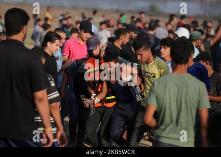 Palästinenser tragen einen verwundeten Demonstranten bei den Zusammenstößen nach den Freitagsprotesten in der Nähe der Grenze zwischen Israel und dem Gazastreifen, 13. September 2019. (Foto von Majdi Fathi/NurPhoto) Stockfoto