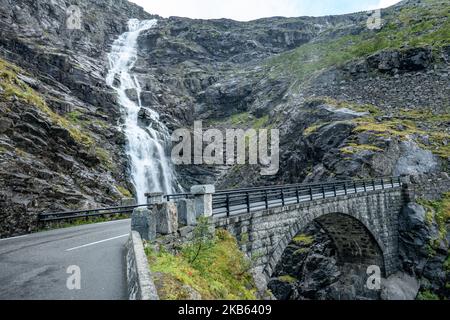 Berühmte Serpentine Scenic Mountain Road Trollstigen oder Trollstigveien, der Trollpfad, eine Bergstraße mit Wasserfällen in der Gemeinde Rauma, Bezirk More Og Romsdal, Norwegen. Die Route ist Teil der Norwegischen Kreisstraße 63, die Andalsnes mit Valldal und Geiranger Fjord verbindet, Trollstigen ist Teil der Norwegischen Panoramastraße Geiranger - Trollstigen. Die Straße ist nur während der Sommersaison geöffnet, sie ist schmal mit scharfen Kurven, aufsteigend 850 Meter, mit einem großen Wasserfall, Stigfossen von einer Höhe von 240 Metern und einer Brücke, Besucherzentrum für Touristen, Besucherplattform. Der Blick auf den Scandi Stockfoto