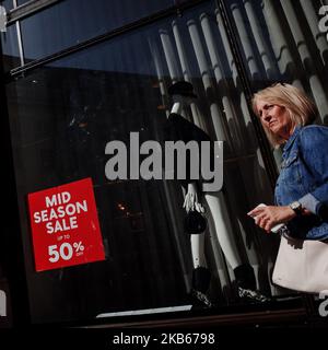 Eine Frau passiert am 18. September 2019 ein Schild mit einem Verkauf zur Saisonmitte im Fenster eines Mango-Bekleidungsladens an der Ecke Glasshouse Street und Regent Street in London, England. Die Verkaufszahlen des britischen Einzelhandels für den Monat August werden morgen vom Office for National Statistics (ONS) veröffentlicht. Die Veröffentlichung im August, die den Monat Juli abdeckt, ergab einen Anstieg der Umsätze im Vergleich zum Vormonat um 0,2 Prozent, wobei die Umsätze in Kaufhaushalten zum ersten Mal im gesamten Jahr 2019 stiegen. (Foto von David Cliff/NurPhoto) Stockfoto