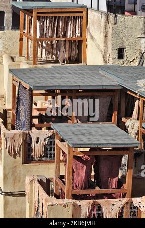 Am 31. Dezember 2015 in Fes (Fez), Marokko, Afrika, hängen Tierhäute von Balkonen, während sie in der Sonne in der Chouara-Gerberei in Fes el Bali oder Old Fes trocknen. Die Chouara Gerberei ist die größte der vier alten Ledergerbereien, die noch in der Medina von Fez geöffnet sind. Das Gerberviertel hat sich zu einer der Hauptattraktionen von Fez entwickelt. Sie können auf den gesamten Bereich herunterschauen und sehen, wie der Prozess durchgeführt wird. Barfuß arbeitende Arbeiter treten in Färbegruben auf Felle. Arbeiter treten die Haut in Erdtanks, die mit Chemikalien oder Farbstoffen gefüllt sind. Die Farben variieren je nach Tag, aber die Häute werden zuerst in Bottichen, die mit einer Mischung gefüllt sind, abgedunkelt Stockfoto