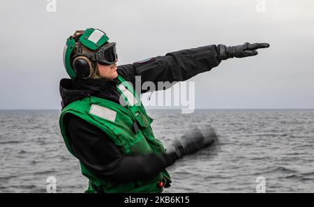 OSTSEE (Okt 24, 2022) Aviation Structural Mechanic Airman Aiden Petric Signals to the pilots in a MH-60R Seahawk Helicopter, Attached to the Helicopter Maritime Strike Squadron (HSM) 79, on the Flight Deck of the Arleigh Burke-class guided-rakete Destroyer USS Roosevelt (DDG 80), Oct 24, 2022. Roosevelt befindet sich im geplanten Einsatzgebiet der US Naval Forces Europe, das von der Sechsten Flotte der USA eingesetzt wird, um die Interessen der USA, der Alliierten und der Partner zu verteidigen. (USA Navy Foto von Mass Communication Specialist 2. Class Danielle Baker/veröffentlicht) Stockfoto