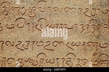 Alter Text, der in den Stein des Brihadeeswarar Temple (auch bekannt als Brihadisvara Tempel, Brihadishvara Tempel, großer Tempel, RajaRajeswara Tempel, Rajarajeswaram und Peruvudayar Tempel) geschnitzt ist ein Hindu-Tempel, der Lord Shiva gewidmet ist und sich in Thanjavur, Tamil Nadu, Indien befindet. Der Tempel ist einer der größten Tempel in Indien und ist ein Beispiel für dravidische Architektur, die während der Chola-Zeit von Raja Raja Chola I erbaut und 1010 n. Chr. fertiggestellt wurde. Der Tempel ist über 1000 Jahre alt und ist Teil des UNESCO-Weltkulturerbes, bekannt als die "Großen Lebenden Chola-Tempel", die aus dem Brihadeeswar bestehen Stockfoto