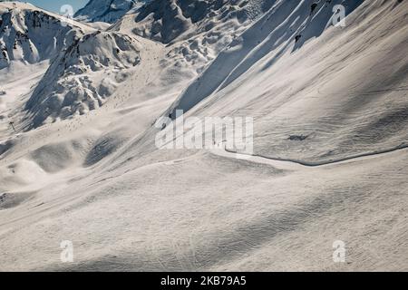 Zwei Skifahrer, die von der Größe und Ungeheuerlichkeit eines Skigebiets in den Alpen im Hintergrund umgeben sind, kommen mehrere Skifahrer auf eine Skipiste La Plagne Alpes Stockfoto