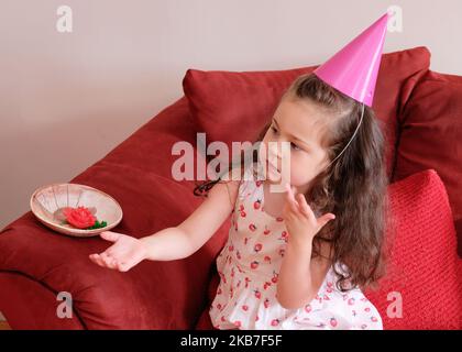 Kleines Mädchen in einer Party hat Kuchen auf der ersten Geburtstagsparty ihres Bruders gegessen Stockfoto