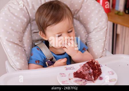 Erste Geburtstagsfeier und zum ersten Mal essen Kuchen für diesen kleinen Jungen Stockfoto