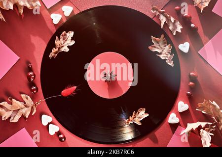Vintage Vinyl Schallplatten in Papierärmel auf schwarzem Hintergrund und Papierärmel. Gelbe Eichenblätter auf rotem Hintergrund mit Herbstverzierungen. Zucker Stockfoto
