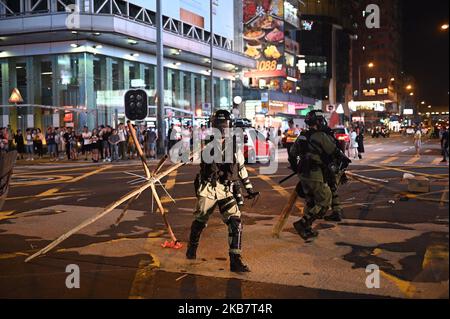 Ein Polizeibeamter wird gesehen, wie er in Mong Kok in Hongkong Barrikaden abzieht am 7. Oktober 2019 wurden prodemokratische Demonstranten monatelang aus Protest der Regierung auf die Straße von Hongkong gebracht. Die Demonstranten haben fünf Hauptforderungen, darunter die Einrichtung einer unabhängigen Untersuchung des Polizeifehlverhaltens während der Behandlung der jüngsten Proteste in Hongkong, hatte die Regierung am 4. Oktober angekündigt, dass sie ein Anti-Maskengesetz mit dem Verbot umsetzen würde, dass Demonstranten während einer legalen oder illegalen Versammlung eine Maske tragen dürfen. (Foto von Vernon Yuen/NurPhoto) Stockfoto