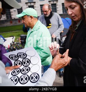 Am zweiten Tag der 'Internationalen Rebellion' der Gruppe in London, England, am 8. Oktober 2019, gibt eine Gruppe von Aktivisten der Gruppe Extinction Rebellion (XR) Aufkleber auf Whitehall aus. Am frühen Dienstagabend meldeten die Metropolitan Police, dass in den zwei Tagen der Proteste in der Stadt bisher insgesamt 531 Festnahmen stattgefunden hatten, wobei Polizeibeamte daran arbeiteten, Menschen und Zelte von vielen der gestern von Aktivisten übernommenen Stätten zu räumen. Ähnliche Blockaden durch das Aussterben Rebellion im April, an Orten wie Oxford Circus und Waterloo Bridge, sahen mehr als 1.000 arres Stockfoto