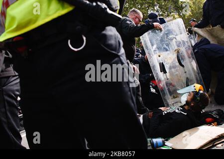 Am dritten Tag der 'Internationalen Rebellion' der Gruppe in London, England, am 9. Oktober 2019 wartet ein Mitglied der klimaaktivistischen Bewegung Extinction Rebellion (XR) auf seine Verhaftung in Whitehall, als Polizisten Elektrowerkzeuge einsetzen, um ihn von einem anderen Demonstranten zu trennen. Polizeibeamte haben heute weiterhin Demonstranten und Zelte von Standorten in ganz Westminster abgestellt, wobei Aktivisten gestern gewarnt wurden, dass sie in einen dafür vorgesehenen Protestbereich um die Nelson-Säule auf dem Trafalgar Square umziehen oder verhaftet werden müssen. Ähnliche Blockaden durch Aussterben Rebellion im April, an Standorten einschließlich O Stockfoto