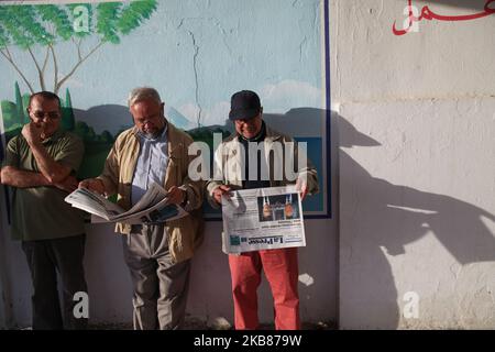 Ein Mann liest eine Zeitung mit einem Titelbild, auf dem die Präsidentschaftskandidaten Kais Saied und Nabil Karoui am 13. Oktober in der Stadt Ennasr, im Gouvernement Ariana, nordöstlich von Tunesien, vor einem Wahllokal Schlange stehen, um seine Stimme für die Stichwahl abzugeben. 2019. (Foto von Chedly Ben Ibrahim/NurPhoto) Stockfoto