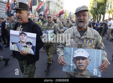 Ukrainische Veteranen, Teilnehmer des Konflikts zwischen den ukrainischen Regierungstruppen und prorussischen Separatisten in den östlichen Regionen, tragen Fotos ihrer Kameraden, die während eines marsches gegen die so genannte "Steinmeier-Formel" beim Krieg getötet wurden, Anlässlich des 77.. Jahrestages der Gründung der ukrainischen Aufständischen Armee und am 14. Oktober 2019 in ZentralKiew, Ukraine. Tausende Aktivisten verschiedener nationalistischer Parteien und Bewegungen marschierten im Zentrum der ukrainischen Hauptstadt und feierten die Gründung der ukrainischen Aufständischen Armee und des Tages des Verteidigers der Ukraine. Die Ukrainerin Stockfoto