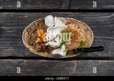 Rending Daging, scharfes indonesisches Eintopf-Rindfleisch und Nasi Goreng, indonesischer oder balinesischer scharfer gebratener Reis auf einem rohen Holztisch. Stockfoto