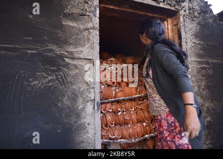 Eine Frau, die am Dienstag, den 22. Oktober 2019, Tontopf-Lampen aus dem Brennplatz für das bevorstehende Tihar- oder Deepawali-Festival auf seinem Workshop auf dem Pottery Square, Bhaktapur, Nepal, herausnimmt. Nepalese Potter arbeitet an ihrer traditionellen Töpferei in kleinem Maßstab in Bhaktapur, Nepal. Bhaktapur ist eine alte Stadt im Kathmandu Valley und wird aufgrund seiner reichen Kultur, Tempel und Holz-, Metall- und Steinkunst von der UNESCO zum Weltkulturerbe erklärt. (Foto von Narayan Maharjan/NurPhoto) Stockfoto