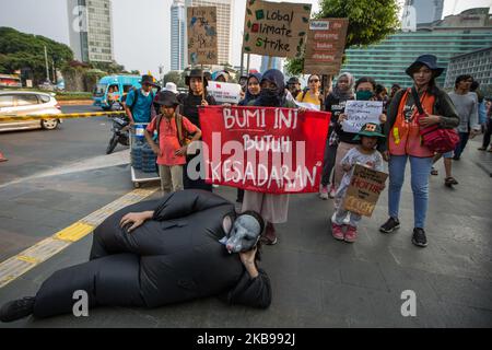 Während einer Demonstration in Jakarta, Indonesien, am 26. Oktober 2019 werden Demonstranten mit einem Banner und Plakaten für den Klimaschutz gesehen. Einige Umwelt-NGOs forderten Präsident Joko Widodo auf, dem Problem der Umweltschäden mehr Aufmerksamkeit zu widmen, insbesondere dem Umgang mit Waldbränden in einer Reihe von Gebieten Indonesiens, deren Auswirkungen zunehmend alarmierend sind. (Foto von Afriadi Hikmal/NurPhoto) Stockfoto