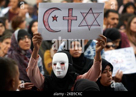 Eine maskierte und verschleierte Frau hält ein Papier mit dem Stern und Halbmond, dem Christain-Kreuz und dem Davidstern. Auf dem Hauptplatz von Toulouse, dem Capitole, versammelten sich Menschen gegen islamophobie. Sie prangern an, was sie als Stigmatisierung des islamischen Glaubens empfinden, da Präsident Macron eine „Gesellschaft der Wachsamkeit“ forderte, um „kleine Zeichen“ zu erkennen, die angeblich eine Radikalisierung ankündigen, wie „interessant in internationalen Nachrichten zu sein“, „Alkohol zu trinken aufhören“, Etc. Sammler prangern auch an öffentlichen Orten eine Intoleranz gegenüber dem muslimischen Kopftuch an. Toulouse. Frankreich. Oktober 27. 2019. (Foto von Stockfoto