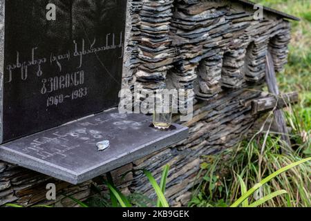 Ein Glas, das am 28. September 2019 auf einem traditionellen Steingrab auf einem alten Friedhof in der Nähe von Mestia, der Hauptstadt der Region Svaneti in Georgien, für die Toten hinterlassen wurde. Svaneti liegt in den Bergen des Zentralkaukasus, umgeben von 3000-5000 Gipfeln, und wird von den Svanen, einer ethnischen Untergruppe Georgiens, bewohnt. Es ist Tradition, mit den Toten Alkohol von den Greaves zu trinken und ihnen ein Glas zu lassen, um ihre Getränke zu genießen. (Foto von Dominika Zarzycka/NurPhoto) Stockfoto