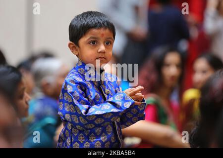 Junge hört Gebete, während Hunderte von hinduistischen Anhängern aarti im BAPS Shri Swaminarayan Tempel während des Annakut Darshan (auch bekannt als Annakut Utsav und Govardhan Puja) durchführen, die am fünften und letzten Tag des Festivals von Diwali stattfindet, Dies markiert den Beginn des Hindu-Neujahrs in Toronto, Ontario, Kanada am 28. Oktober 2019. Annakut, was einen „großen Berg an Nahrung“ bedeutet, der Gott als Zeichen der Hingabe angeboten wird. BAPS (Bochasanwasi Shri Akshar Purushottam Swaminarayan Sanstha) ist eine Sekte des Hinduismus Diksha Vidhi und ihrer Tempel, obwohl sie vielen Hindu-Gottheiten gewidmet ist, als Stockfoto