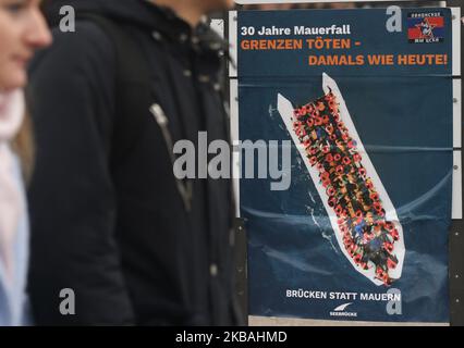 Menschen passieren in der Nähe eines Plakats zum 30.. Jahrestag des Mauerfalls, das sich in der Nähe eines Abschnitts der ehemaligen Berliner Mauer, der East Side Gallery, befindet. Am Samstag, den 9. November 2019, in Berlin, Deutschland. (Foto von Artur Widak/NurPhoto) Stockfoto