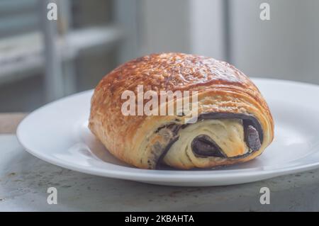 Pain au Chocolat auf einem weißen Gericht mit natürlichem, hellem „Schokoladenbrot“ mit foled-Teig. Stockfoto