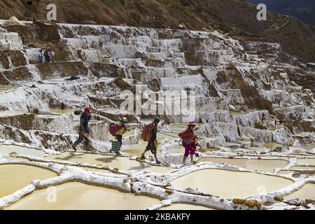 Die Arbeiter bereiten sich darauf vor, am 14. Juli 2014 Salz aus den Verdunstungsteichen in der Stadt Maras in der Nähe von Cusco Peru im Heiligen Tal der Inkas zu sammeln. Diese Teiche sind seit den Tagen der Inka in Gebrauch. Salz wird durch Verdampfen von salzigem Wasser aus einem unterirdischen Strom gewonnen. Der Fluss wird durch ein System winziger Kanäle geleitet, die so konstruiert sind, dass das Wasser allmählich auf mehrere hundert alte terrassenförmige Teiche abfließt. Während Wasser in der wasserverdampften Andenluft verdampft, fällt das Salz als weiße Kristalle an den Wänden und am Boden des Teiche aus. Foto von Tom O'Neill (Foto von Thomas O'Neill/NurPhoto) Stockfoto