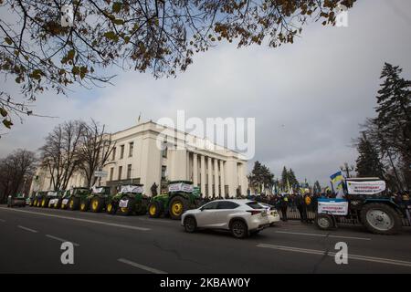 Traktoren ukrainischer Bauern mit Plakaten mit der Aufschrift „Nein zum Verkauf ukrainischen Landes!“ Werden vor dem Parlament geparkt, während einige hundert Menschen gegen die eventuelle Annahme des Grundmarktgesetzes vor Werchowna Rada in Kiew, Ukraine, am 13. November 2019 protestieren. In der Nähe des ukrainischen Parlamentsgebäudes findet eine Kundgebung statt, die von Gegnern des Landmarktes abgehalten wird. Der ukrainische Präsident Zelensky sagte in einer am 11. November 2019 veröffentlichten Videoansprache an die Nation, dass die Frage des Verkaufs von Ackerland an Ausländer und von Ausländern gegründete Unternehmen einer All-Ukrainerin vorgelegt wird Stockfoto